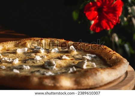 Four cheese italian pizza on a wooden plate with floral b ackground