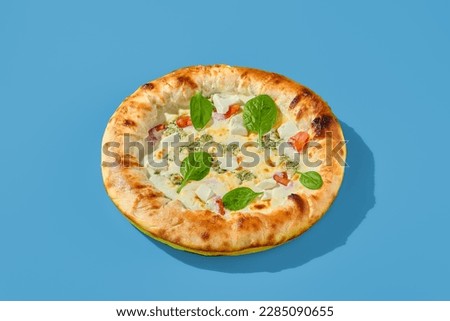 Four cheese pizza with tomatoes and spinach on a bright blue background. Minimalist style, side view. Perfect for a modern food photography, takeout or casual meal.
