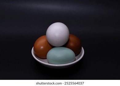 Four chicken eggs of different colors on a black background. Without packaging. White egg, brown egg, blue chicken egg. Different on the outside but the same on the inside - Powered by Shutterstock