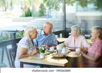 Four childhood friends gathered together in outdoor cafe after long separation and remembering funny stories from their past - Powered by Shutterstock