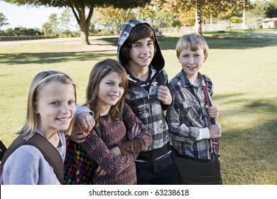 Four children (10 to 15 years) posing together with school book bags