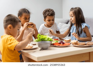 Four children gather around a table, assembling sandwiches with fresh vegetables and spreads, highlighting teamwork and healthy eating habits in a cozy setting. - Powered by Shutterstock