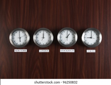 Four clocks with different time on Teak background