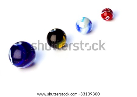 Four colored glass balls known as marbles, on white