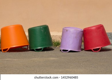 Four Colored Plastic Containers Lie Upside Down Near The Plastered Wall