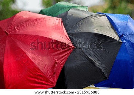 four colorful umbrellas on a blurred background. red, black, blue and green outdoors with fresh trees