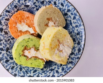 Four Colourful Chiffon Cake Slide With Cream And Different Flavour On Blue Plate Isolated In White Background.