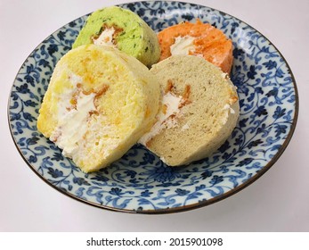 Four Colourful Chiffon Cake Slide With Cream And Different Flavour On Blue Plate Isolated In White Background.