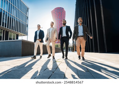 Four confident businessmen walking outdoors in a modern cityscape, dressed in formal suits, casting long shadows, exuding professionalism, teamwork, and leadership in an urban business environment - Powered by Shutterstock