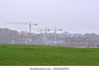 Four construction site cranes in the distance in foggy day - Powered by Shutterstock