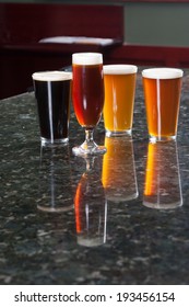 Four Different Beers On Granite Bar Top Reflection