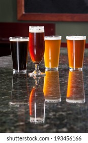 Four Different Beers On Granite Bar Top Reflection