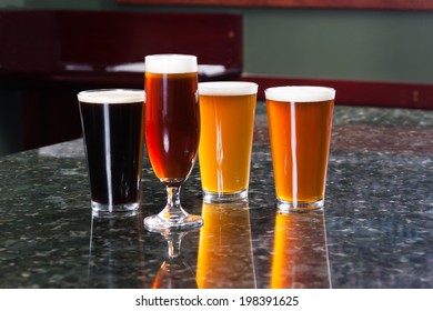 Four Different Beers On Granite Bar Top Reflection