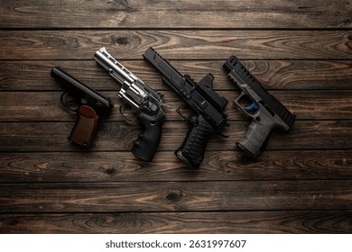 Four different handguns displayed side by side on wooden planks.