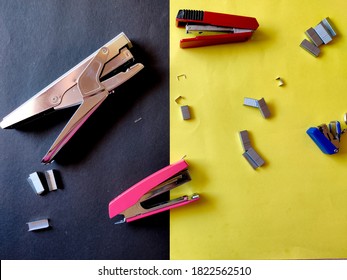 Four different sized staplers and stapler pins isolated on yellow background. Top view