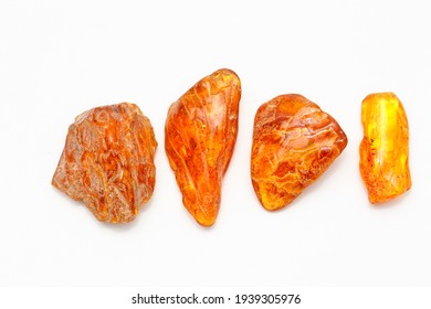 Four Different Transparent Polished Yellow Amber Pieces On A White Background. Sun Stone. Natural Mineral Material For Jewelry. Amber Texture. Copal. Multicolored Yellow Background. Ancient  Resin