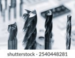 Four different types of drill bits are shown, with one of them being a spiral. Concept of precision and technicality, as these tools are commonly used in manufacturing and construction