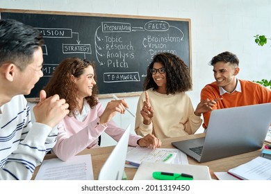 Four Diverse Multiracial Young Happy Colleagues Students Business Startup Gen Z Team Discussing Project Together In Classroom Office Using Laptops. International Teamwork Diversity Concept.