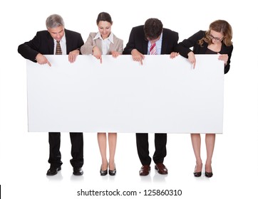 Four Diverse Professional Businesspeople Holding A Blank Banner Or Horizontal Sign For Your Text Or Advertisement Isolated On White