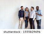 Four diverse young business people pose near grey white wall studio background copy space for ad text, millennial generation arab african european professionals, human resources, new workforce concept