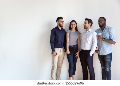 Four diverse young business people pose near grey white wall studio background copy space for ad text, millennial generation arab african european professionals, human resources, new workforce concept