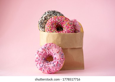 four donuts with glaze in a paper bag on a pink background