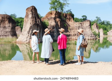 Four elderly Asian women admiring scenic rock formations lake. Women wearing sun hats, casual outfits, holding water bottles. Enjoying tranquil environment, bonding and sharing moments of happiness - Powered by Shutterstock