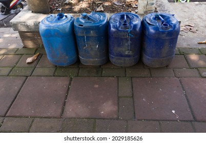 Four empty blue plastic Jirigens are laid out on a sidewalk.