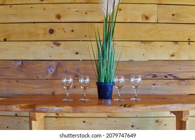 Four Empty Glass Glasses On Table And Wooden Background With A Plant In The Middle. Waiting For A Wine Tasting At A Winery In Argentina. Horizontal