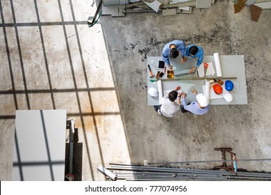 Four engineers in team making a discussion at construction site with several color helmets, taken from  bird eye views or top view - Powered by Shutterstock