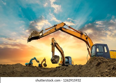 Four excavators work on construction site at sunset