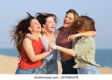 Four excited friends jumping and celebrating vacation on the beach - Shutterstock ID 2070481478