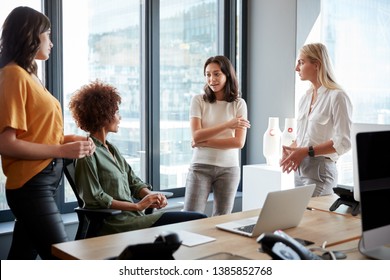Four female colleagues in discussion at a desk in a creative office, three quarter length - Shutterstock ID 1385852768