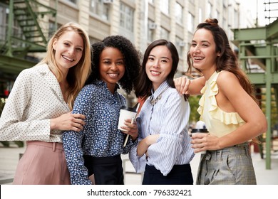 Four female coworkers smiling to camera outside