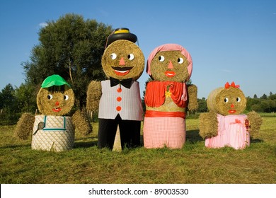 Four figures made out of straw bales, man, woman, boy, girl, father, mother daughter, son, on a meadow