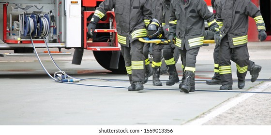 Four Firemen Stretcher Bearer After The Road Accident On The Street And The Fire Engine