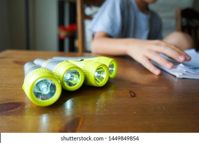 Four Flashlights On A Table For A School Science Experiment. Hands Of A Sixth Grader In The Back In Bokeh. 