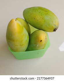 Four Fresh Mangoes On Tupperware