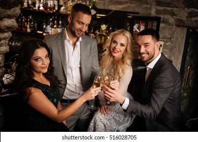 Four friends with champange glasses celebrating and toasting in restaurant