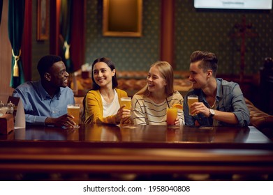 Four friends drinks alcohol at the counter in bar