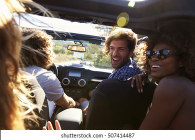 Four friends driving in an open top car, rear passenger POV
