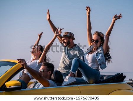 The four friends fool around in a yellow cabriolet