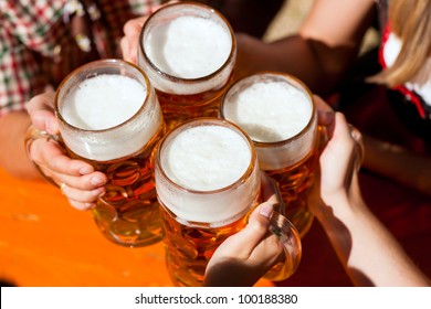 Four Friends With A Fresh Beer In A Beer Garden, Close-up On Beer Stein