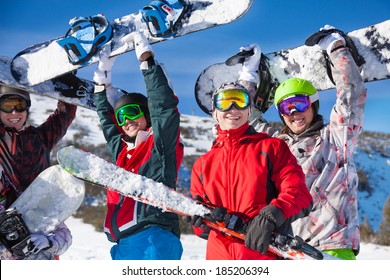 Four Friends Holding Snowboards And Skies