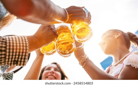 Four friends, men and women, having fun in beer garden clinking glasses with beer at Oktoberfest or Dult in germany - Powered by Shutterstock