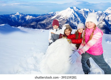 Four Friends Rolling The Huge Snowball On Hill