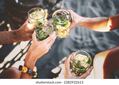 Four friends toasting with mojito glasses while sitting at a beach bar in the summer - hands holding drinks on sandy beach. - Powered by Shutterstock