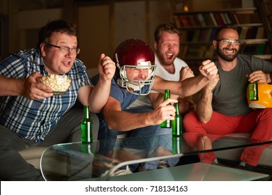 Four Friends Watching American Football Game On Television