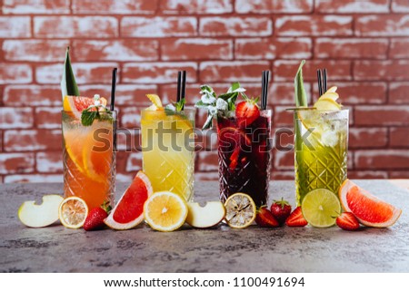 Four frowzen cocktails on table with tasty fruits on loft background.