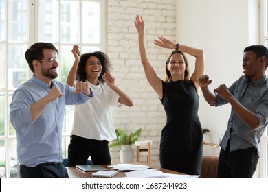 Four Funny Active Multi-ethnic Business Team Staff Members Dancing Moving Listening Music Gathered In Office Board Room. Succeed Common Goal Feels Happy, Corporate Holiday Event Celebration Concept